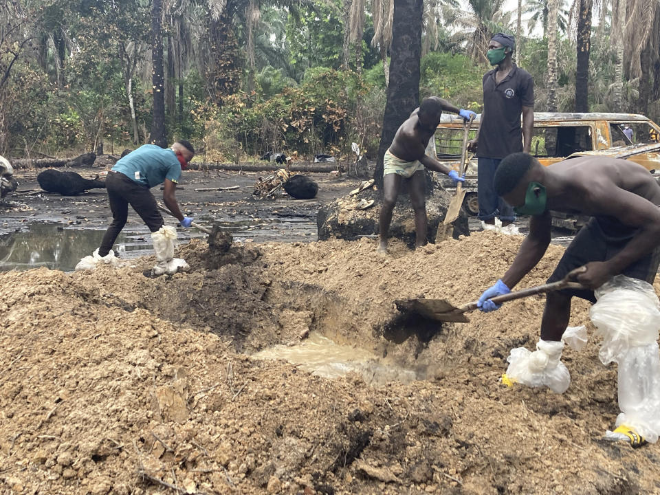 Volunteers bury the charred bodies of victims of an illegal refinery explosion for a funeral in Imo, southeastern Nigeria, Tuesday, April 26, 2022. Remains of the workers and traders who died when an illegal refinery exploded in southeast Nigeria were gathered and buried even as a local official accused security agencies of "sabotage" in the incident. (AP Photo/Chinedu Asadu)