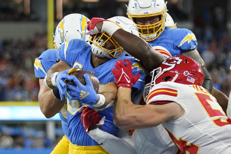 Los Angeles Chargers running back Austin Ekeler, left, scores a touchdown as he is face masked by Kansas City Chiefs linebacker Nick Bolton as linebacker Leo Chenal, right, tries to stop him during the first half of an NFL football game Sunday, Nov. 20, 2022, in Inglewood, Calif. (AP Photo/Jae C. Hong)