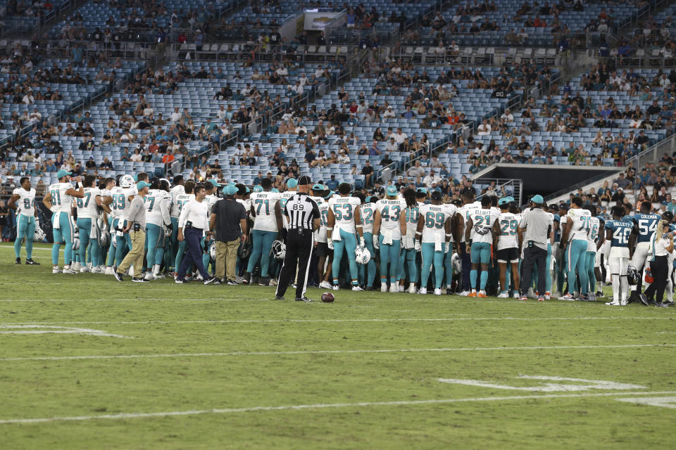 Players gather on the field after an injury to Miami Dolphins wide receiver Daewood Davis during the second half of an NFL preseason football game against the Jacksonville Jaguars, Saturday, Aug. 26, 2023, in Jacksonville, Fla. (AP Photo/Gary McCullough)