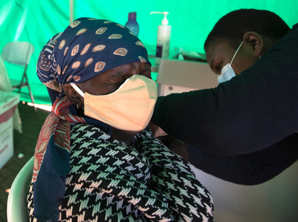 A retiree receives the first dose of the Pfizer coronavirus vaccine from a health worker inside a tent, during a mass vaccination program for the elderly at the clinic outside Johannesburg, South Africa, Monday, May 24, 2021. South Africa aims to vaccinate 5 million of its older citizens by the end of June. (AP Photo/Themba Hadebe)