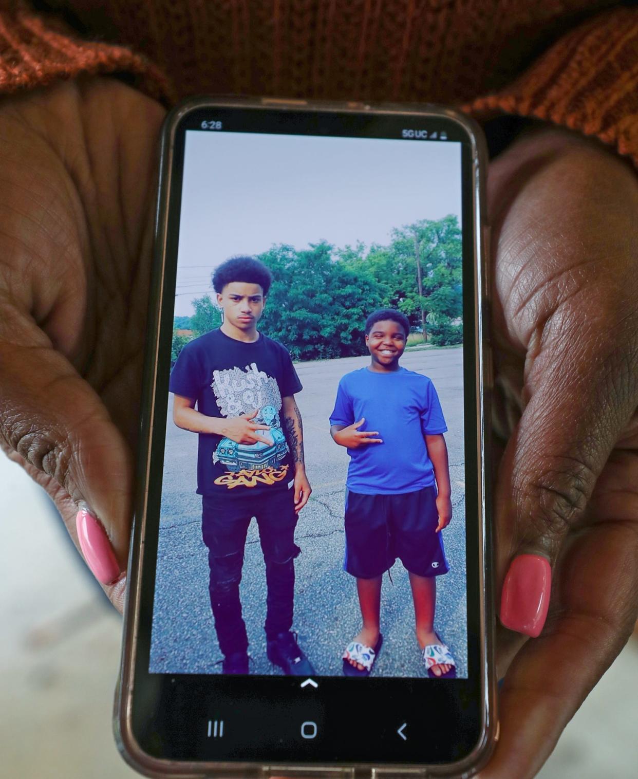 LaTia Snyder shows a photo of her nephew, the late 17-year-old Antenio Louis, with her son Keilen, 12.