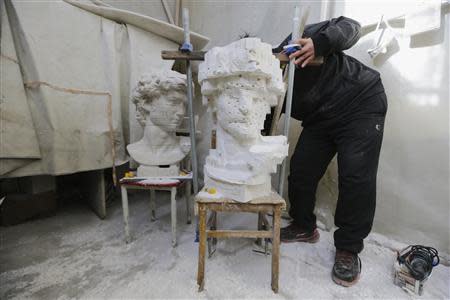 An assistant of Chinese artist Li Hongbo adjusts the chair carrying a paper replica of the Sculpture of David, which will be made according a David statue (L), at Li's studio on the outskirts of Beijing, January 20, 2014. REUTERS/Jason Lee