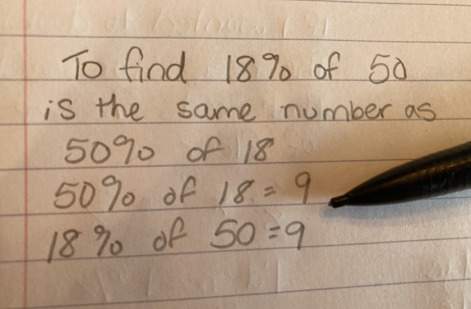 Handwritten math showing that 18% of 50 equals 50% of 18, both equal 9, with a pen resting on paper