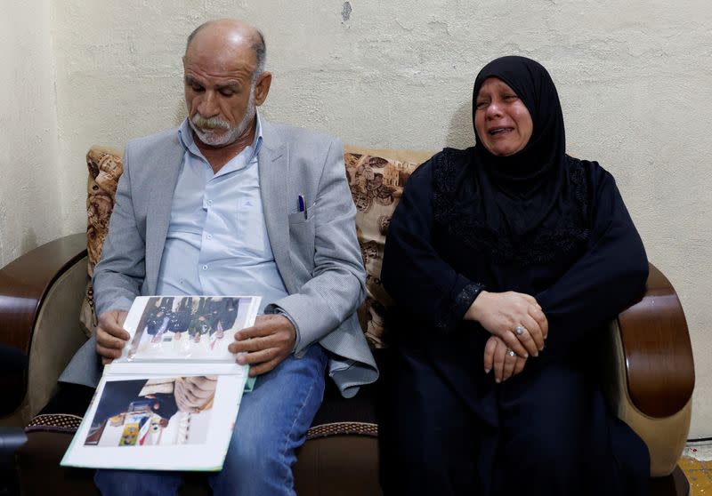 Majid Mohammed looks at pictures of his son who disappeared after the Camp Speicher massacre in 2014, as his wife, Nadia Jasim, reacts during an interview with Reuters, in Baghdad