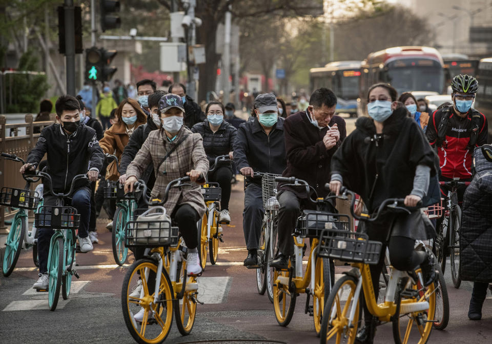 Image: Chinese commuters wear protective masks as they ride bikes and scooters in the central business district during rush hour (Kevin Frayer / Getty Images file)