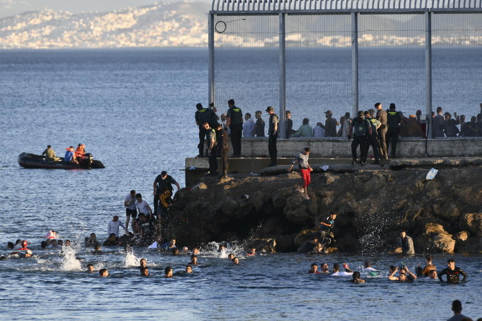 Spanish Guardia Civil officers try to stop people from Morocco swimming and entering into the Spanish territory at the border of Morocco and Spain, at the Spanish enclave of Ceuta on Monday, May 17, 2021. Authorities in Spain say that around 1,000 Moroccan migrants have crossed into Spanish territory (Antonio Sempere/Europa Press via AP)