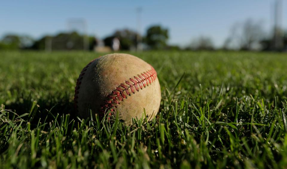 A baseball rests on a high school baseball field.