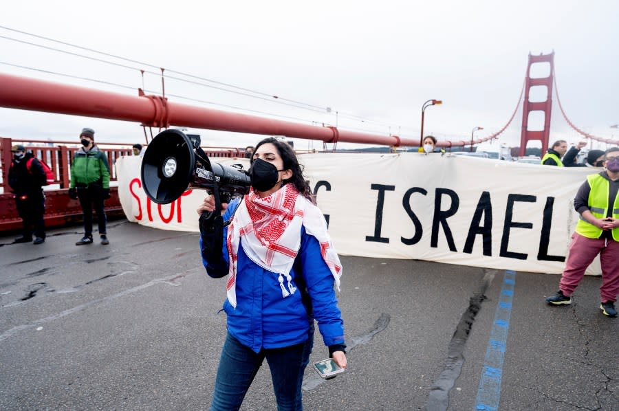 Aysha Abraibesh leads a chant as pro-Palestinian demonstrators block commute traffic on the Golden Gate Bridge on Wednesday, Feb. 14, 2024, in San Francisco. About 20 protesters, some holding signs against Israeli’s military offensive in Rafah, blocked traffic in both directions for about 15 minutes. (AP Photo/Noah Berger)