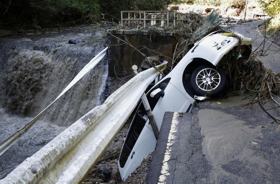 A vehicle falls off collapsed road in the typhoon-hit Kakuda city, Miyagi prefecture, northern Japan, Sunday, Oct. 13, 2019. Rescue efforts for people stranded in flooded areas are in full force after a powerful typhoon dashed heavy rainfall and winds through a widespread area of Japan, including Tokyo.(Kyodo News via AP)