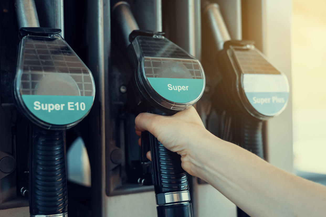 An unidentifiable person uses the fuel pump at a petrol station