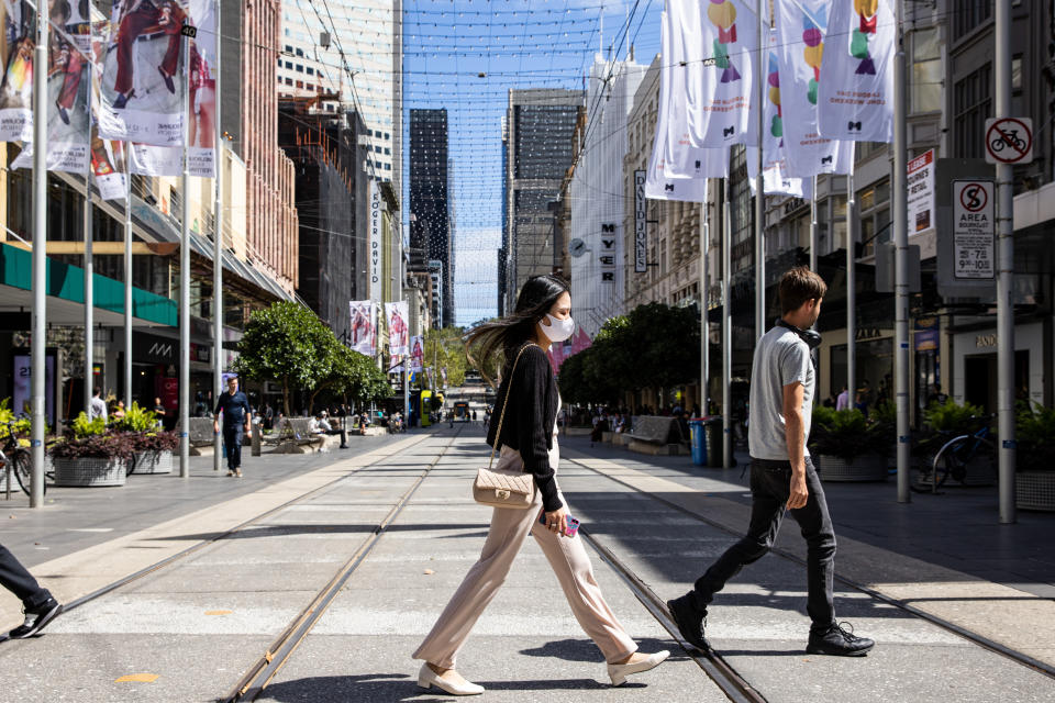 A woman is seen wearing a face mask as she crosses Bourke Street in Melbourne during an Omicron wave. Source: AAP