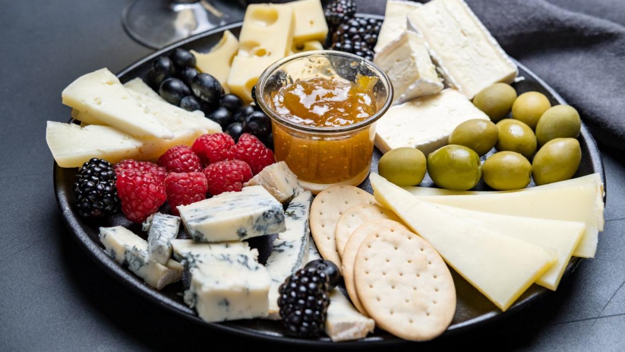 cheese board parmesan, pecorino, gorgonzola, brie cheese and berries, olives and jam and crackers appetizer for wine, festive serving for dinner or lunch