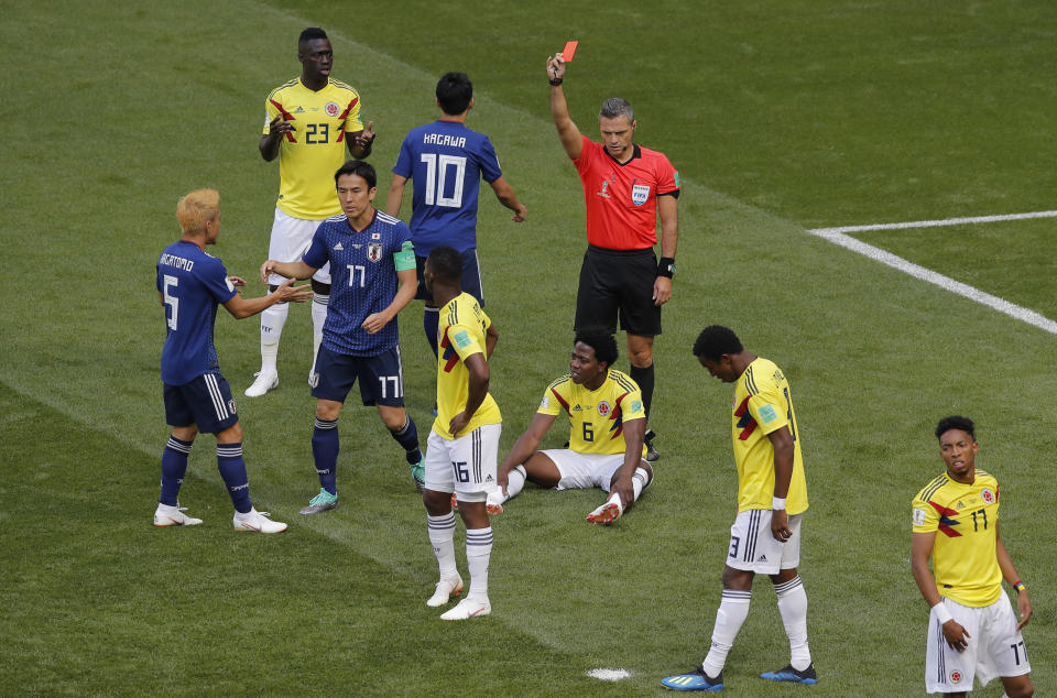 Referee Damir Skomina from Slovenia shows a red card to Colombia’s seated Carlos Sanchez