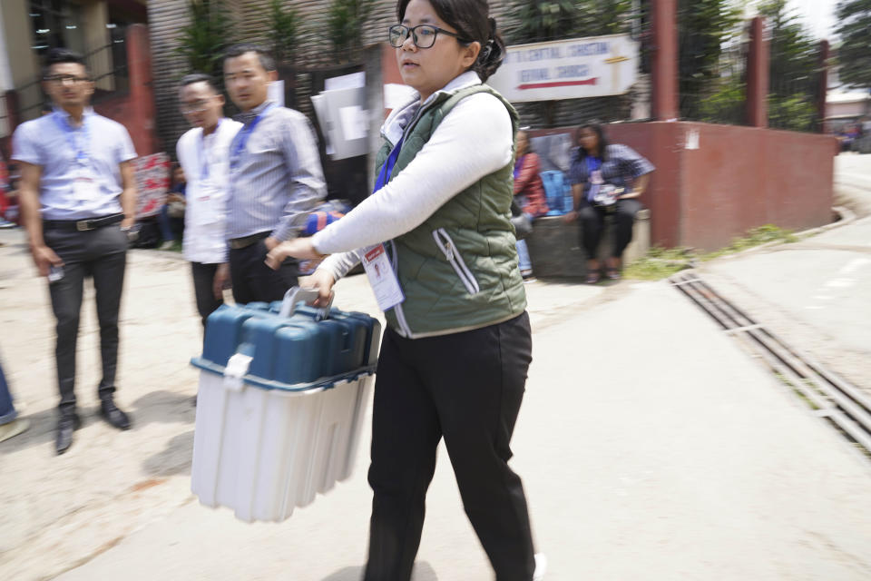 Presiding Officer Neichutuonuo Yhome, 27, carries an electronic voting machine and proceeds towards her polling station on the eve of polls in Kohima, in the northeastern Indian state of Nagaland, Thursday, April 18, 2024. (AP Photo/Yirmiyan Arthur)