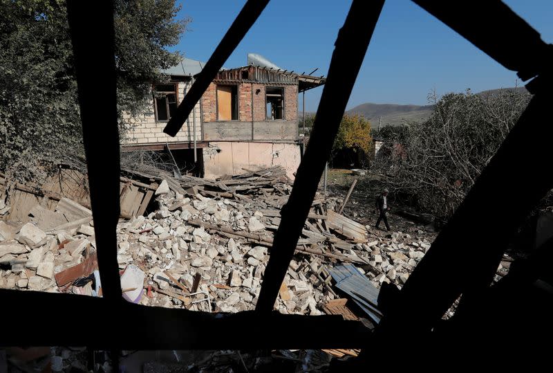 A man walks next to the ruins of a house that was destroyed by recent shelling during the military conflict over the breakaway region of Nagorno-Karabakh, in Martuni