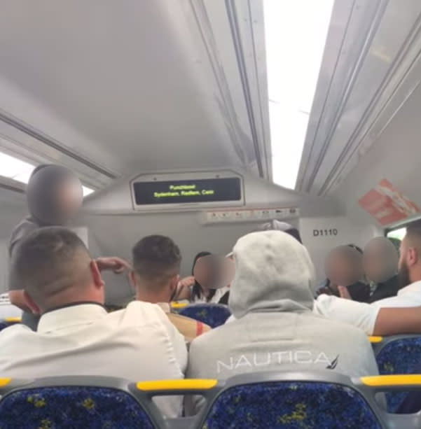 A still showing a Sydney woman confronting large group of commuters who were being loud and rude on a train on a Bankstown line.