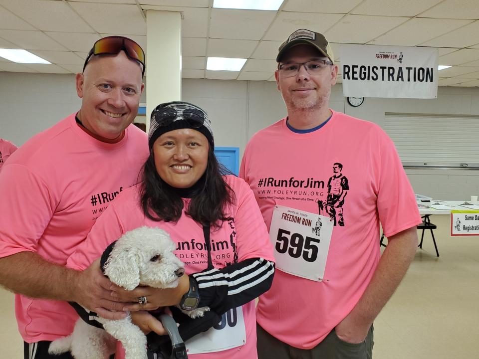 Russ Kemp, Mimi Kemp and Joshua Burke of Wolfeboro are seen prior to running for the eighth time in the eighth annual James Foley Freedom Run Saturday, Oct. 15, 2022. All three attended school with James. Vinnie the dog joined them for support.