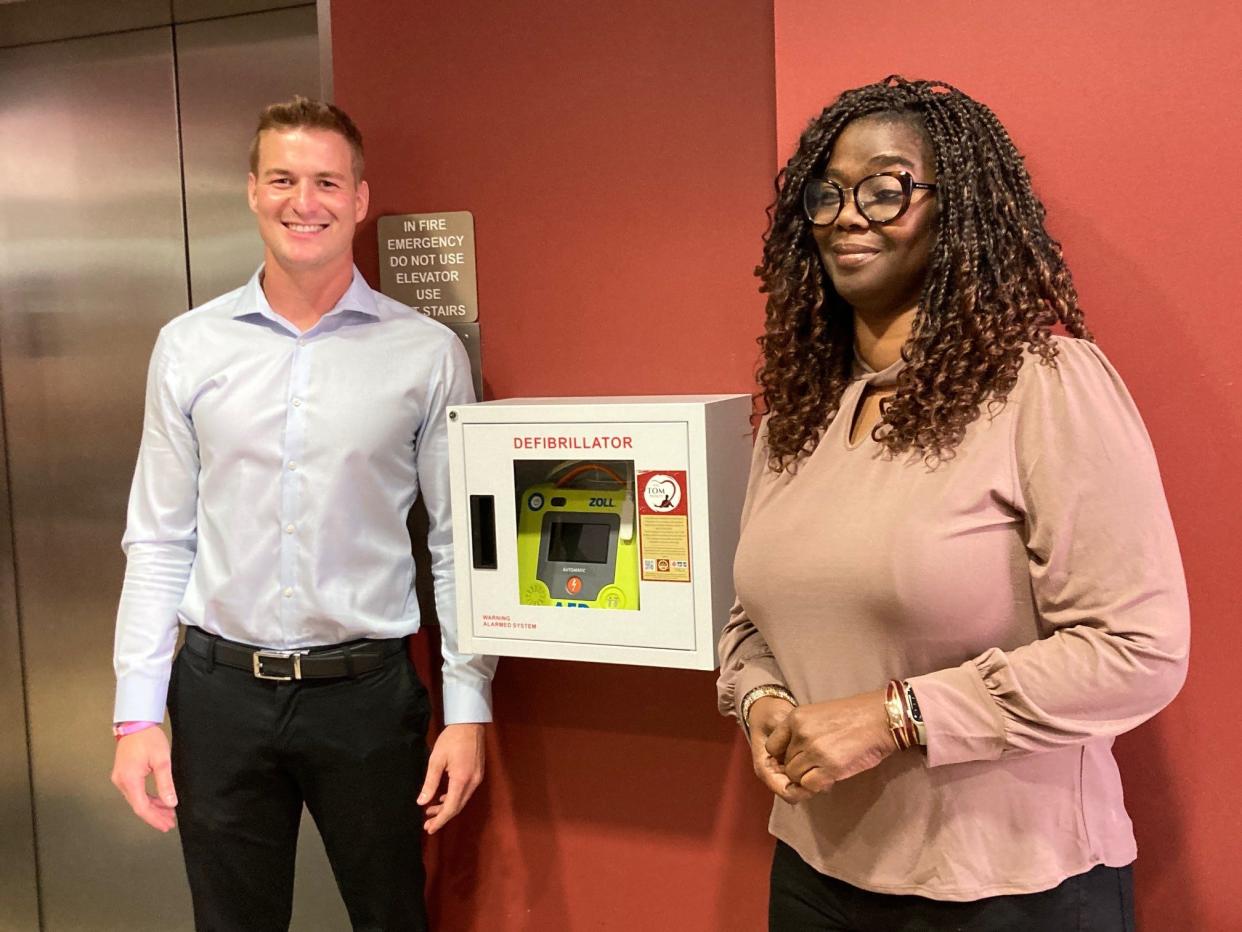 Florida State University doctoral student Chris Hagemeyer (left) and Cathy Idowu (right) stand next to the first installed defibrillator of the TOM Project on Oct. 14, 2022.