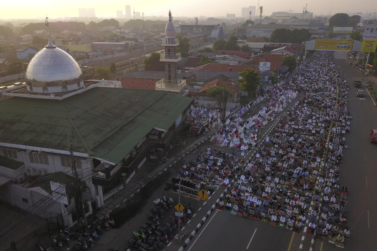 In this photo taken using a drone, Muslims attend Eid al-Fitr prayers marking the end of the holy fasting month of Ramadan on a street in Bekasi, West Java, Indonesia, Monday, May 2, 2022. (AP Photo/Achmad Ibrahim)