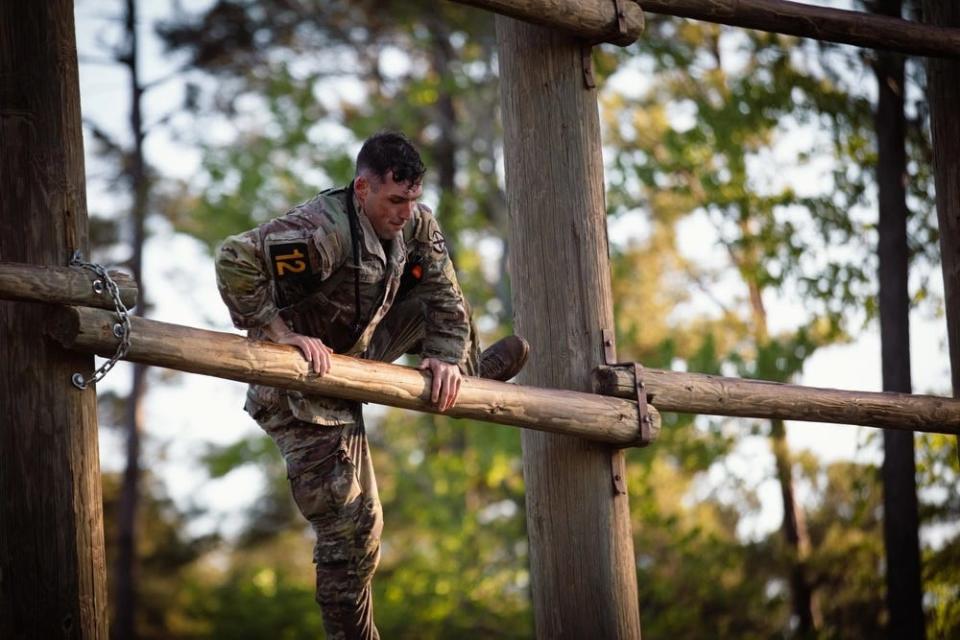 A US Army soldier climbs up an obstacle during a competition