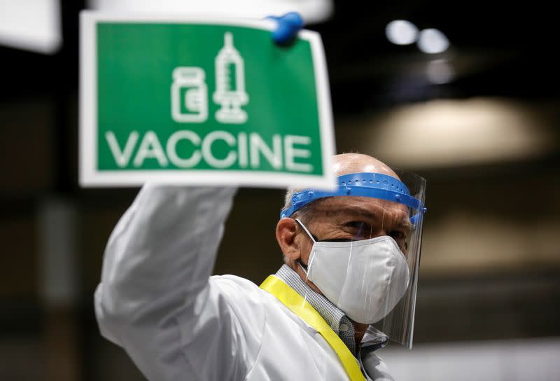 Thayer holds up a sign to signal his station needs more vaccine doses as people attend a coronavirus disease (COVID-19) vaccination site at Lumen Field Event Center in Seattle