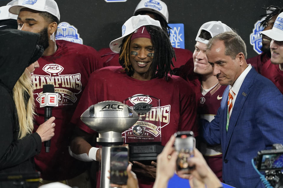 Florida State running back Lawrance Toafili, center, receives the most valuable player of the game award after the team's win over Louisville in the Atlantic Coast Conference championship NCAA college football game, Saturday, Dec. 2, 2023, in Charlotte, N.C. (AP Photo/Erik Verduzco)