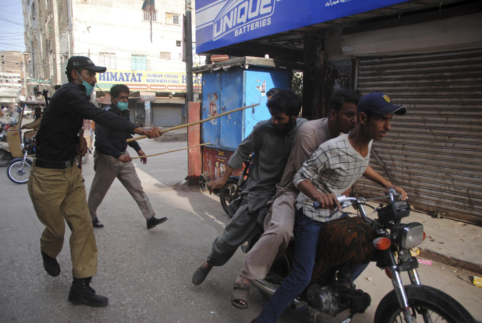 FILE - In this Monday, April 13, 2020 file photo, police officers try to restrict people from defying the nation-wide lockdown to curb the spread of the coronavirus, in Hyderabad, Pakistan. Wealthier Western countries are considering how to ease lockdown restrictions and start taking gradual steps toward reviving business and daily life. But many developing countries, particularly in the Middle East and Africa, can hardly afford the luxury of any misstep. (AP Photo/Pervez Masih, File)