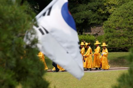 People in traditional dress walk past a South Korean flag in the foreground after the arrival of U.S. President Donald Trump and Secretary of State Mike Pompeo to meet with South Korean President Moon Jae-in, at the Blue House, in Seoul