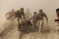 <p>Members of the U.S. Navy carry a comrade wounded by an explosion to a medevac helicopter in Kandahar province in southern Afghanistan, Oct. 2, 2010. (Photo: Finbarr O’Reilly/Reuters) </p>