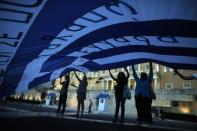 Anti-austerity demonstrators hold up a giant Greek flag in front of parliament in Athens, July 22, 2015. REUTERS/Ronen Zvulun