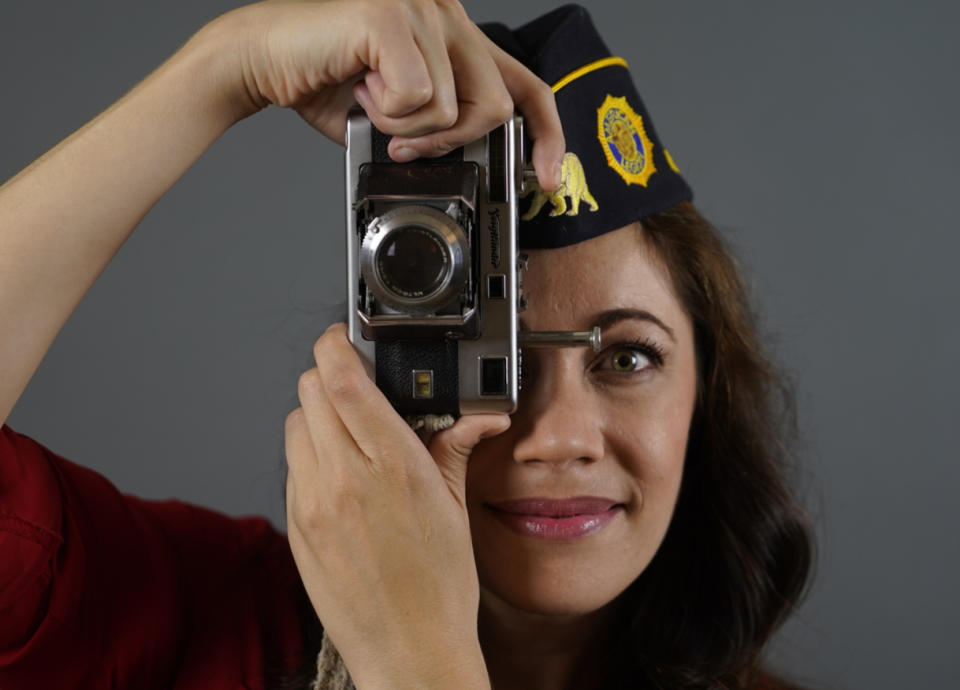 In this June 30, 2021, Los Angeles-based producer, actress and Marine Corps veteran Jennifer Brofer poses with a vintage Voigtlander Vitessa film camera gifted by her grandfather at her apartment in Los Angeles. Brofer will never forget the loud, popping noise. It was on a hot July afternoon in 2010 when her convoy rolled over an IED on a road in Helmand Province four months into her deployment to Afghanistan. Her heart froze as she and her fellow Marines stopped and realized what had occurred. But what followed were only the sounds of daily life. Brofer, 38, who now works in the film industry in Hollywood, said she feels proud to have served "shoulder-to-shoulder with my male marine counterparts" in a time of war. (AP Photo/Damian Dovarganes)