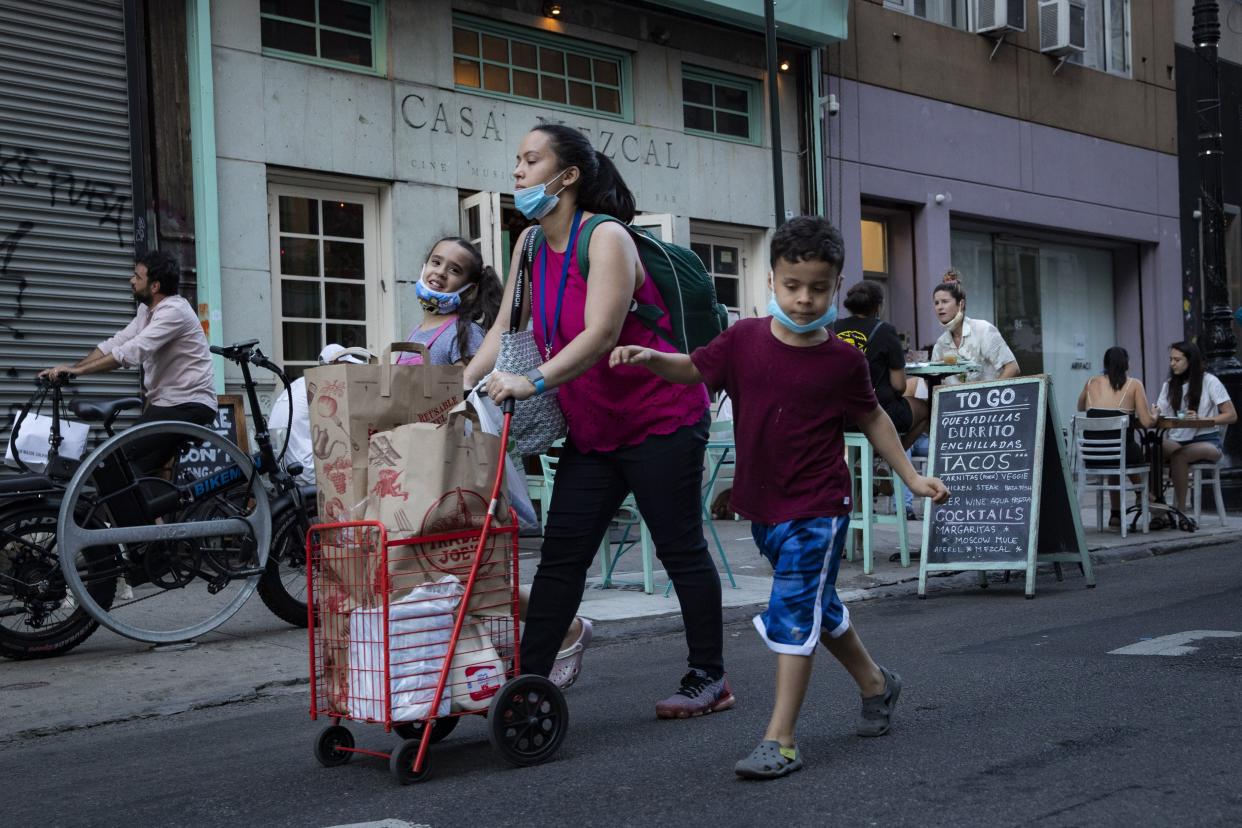 Pedestrians pass customers dining outside Casa Mezcal on Monday, June 22, 2020, in New York. New York City ventured into a crucial stage of reopening as stores let people in Monday, offices brought workers back, restaurants seated customers outdoors and residents both welcomed and worried about rebounding from the nation's deadliest coronavirus outbreak.