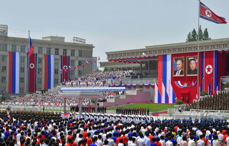 A crowd in Pyongyang stands under portraits of Kim and Putin.