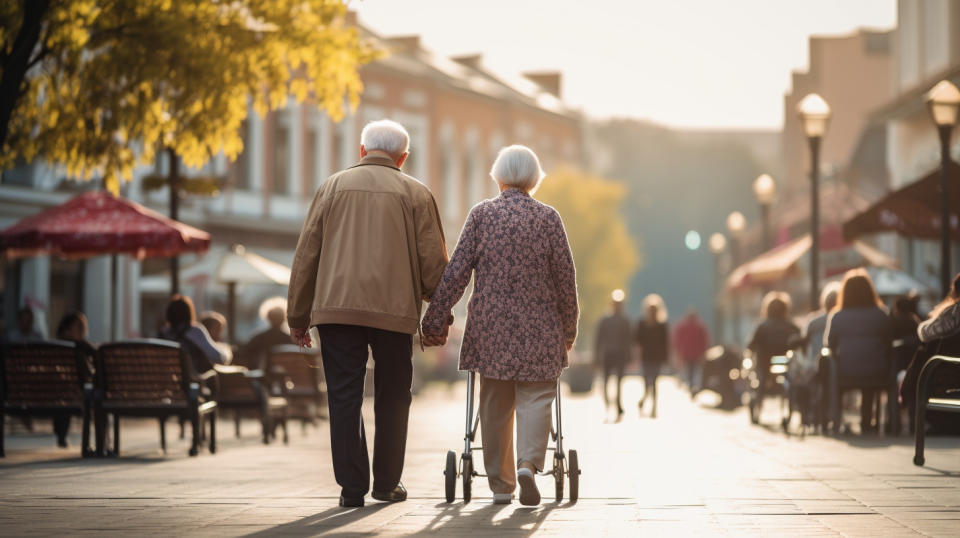 A senior couple walking hand-in-hand in a senior housing facility.