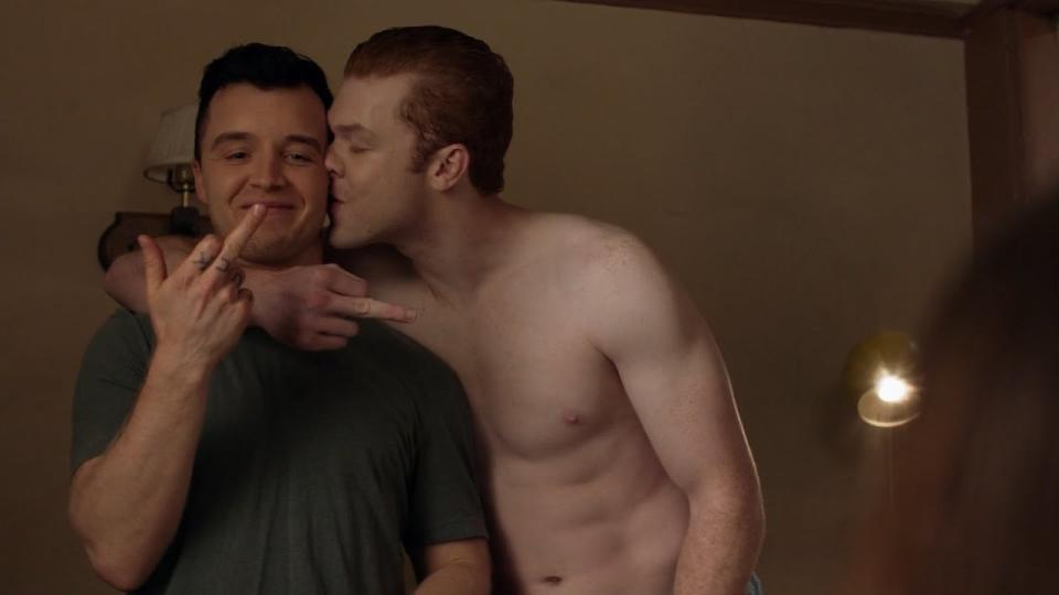 "Shameless" character Ian hugging and kissing Mickey while they hold up their middle fingers