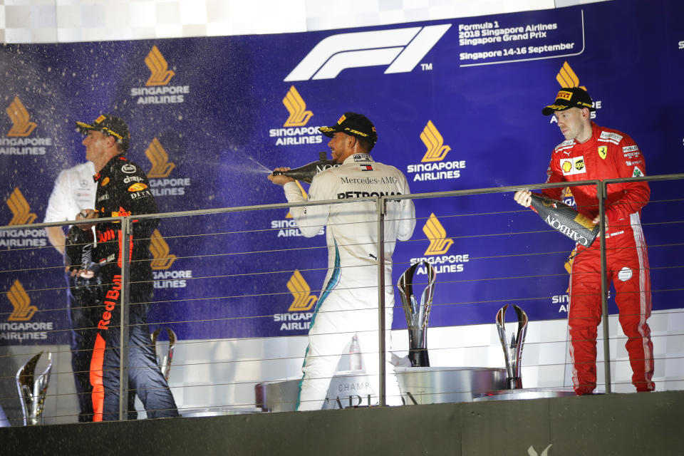Mercedes driver Lewis Hamilton of Britain, center, sprays champagne at Red Bull Racing driver Max Verstappen of Netherlands, left, as he celebrates after winning the Singapore Formula One Grand Prix, next to Ferrari driver Sebastian Vettel of Germany, at the Marina Bay City Circuit in Singapore, Sunday, Sept. 16, 2018. (AP Photo/Vincent Thian)