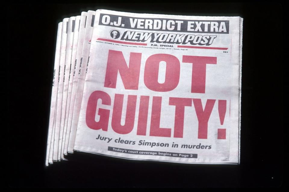 a stack of newspapers with the phrase not guilty in red letters followed by the statement jury clears simpson in murders