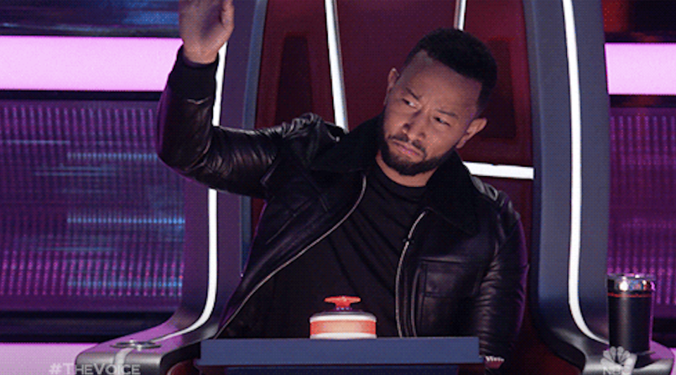 John Legend raising his hand in praise 