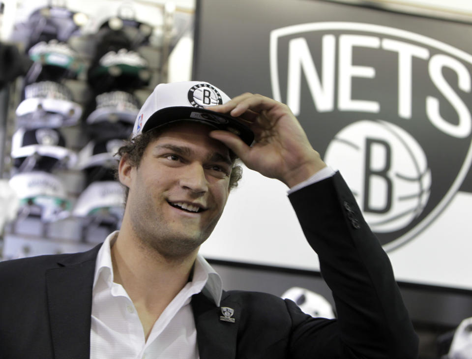 Brooklyn Nets basketball player Brook Lopez tries on a hat with the new Nets' logo during a news conference to unveil the new logos in the Brooklyn borough of New York, Monday, April 30, 2012. The Nets will be moving from New Jersey to the new Barclays Center in Brooklyn, New York for the 2012-2013 NBA basketball season. (AP Photo/Seth Wenig)