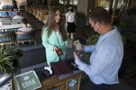 A restaurant employee, right, checks a visitor's COVID-19 vaccination QR code at the entrance of a restaurant in Moscow, Russia, Tuesday, June 22, 2021. As proof of vaccination for entering a restaurant, customers must visit a government website and get a QR code, a digital pattern designed to be read by a scanner. (AP Photo/Pavel Golovkin)