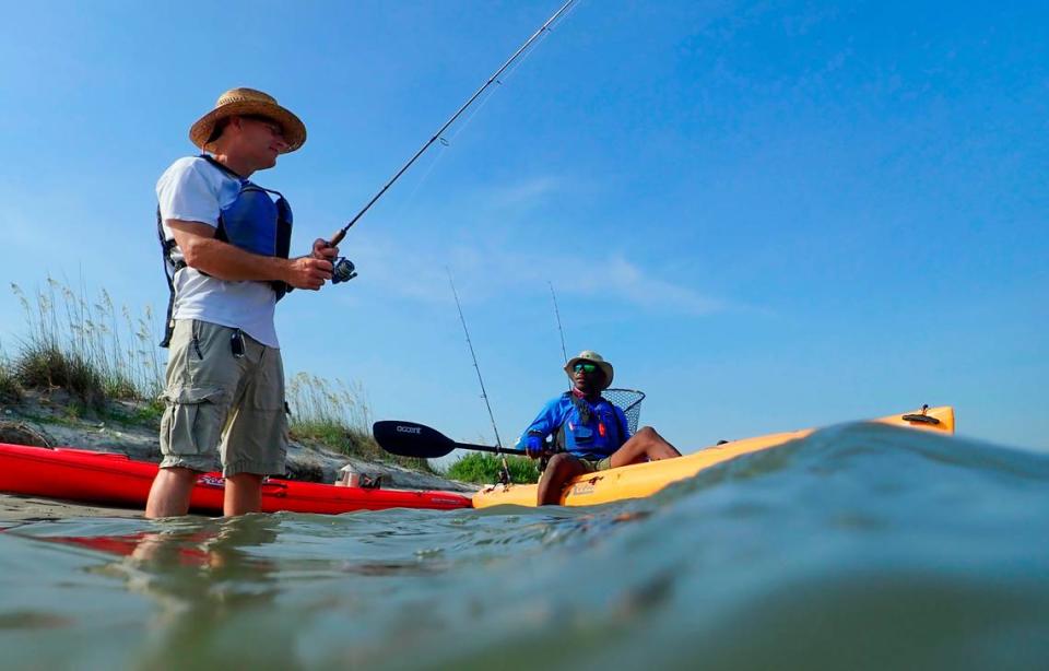 Ken Heil (left) an angler from Maryland, talks with fishing guide Mike Eady while wade fishing in Midway Inlet, Pawleys Island.