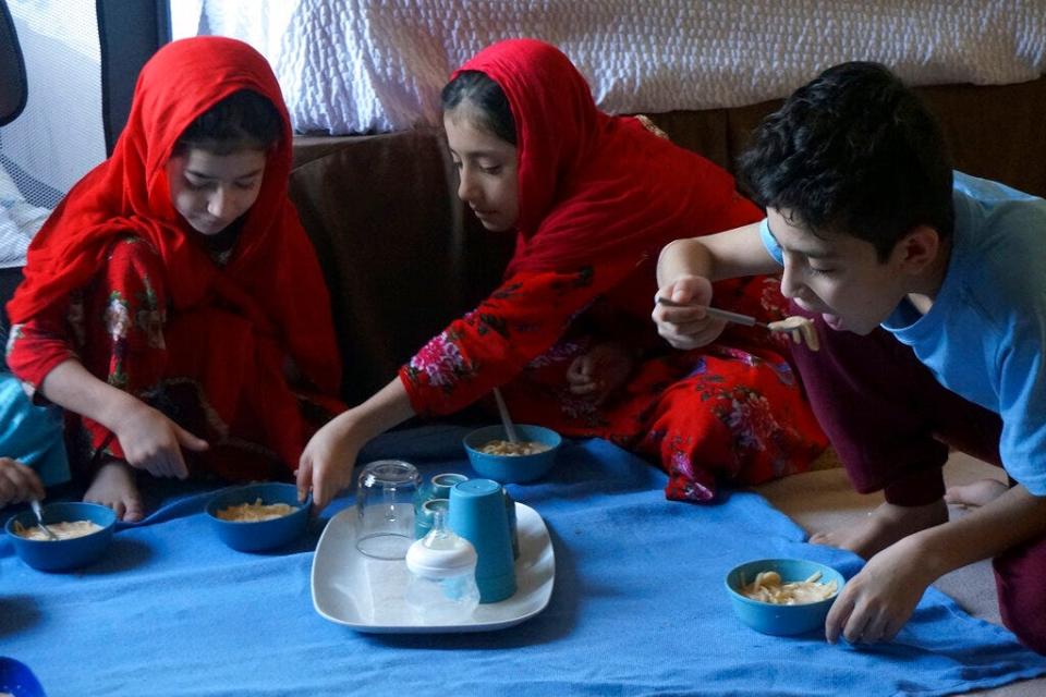 The three oldest Sultani children, from left, Sana, 8; Elaha, 9, and Shafiullah, 11, eat a midday meal prepared by their mother in the motel room the family shares in El Paso on Saturday, March 26, 2022. The children, their three younger siblings and parents were evacuated from Afghanistan when the Taliban regained power last summer.