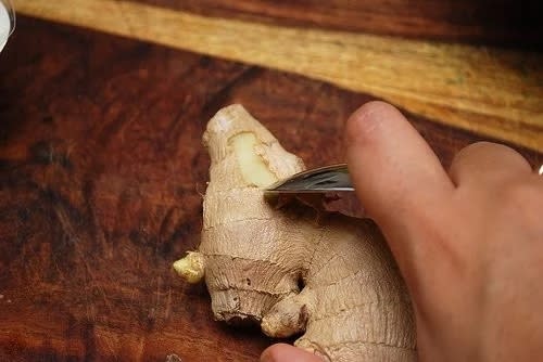 someone peeling ginger with a spoon