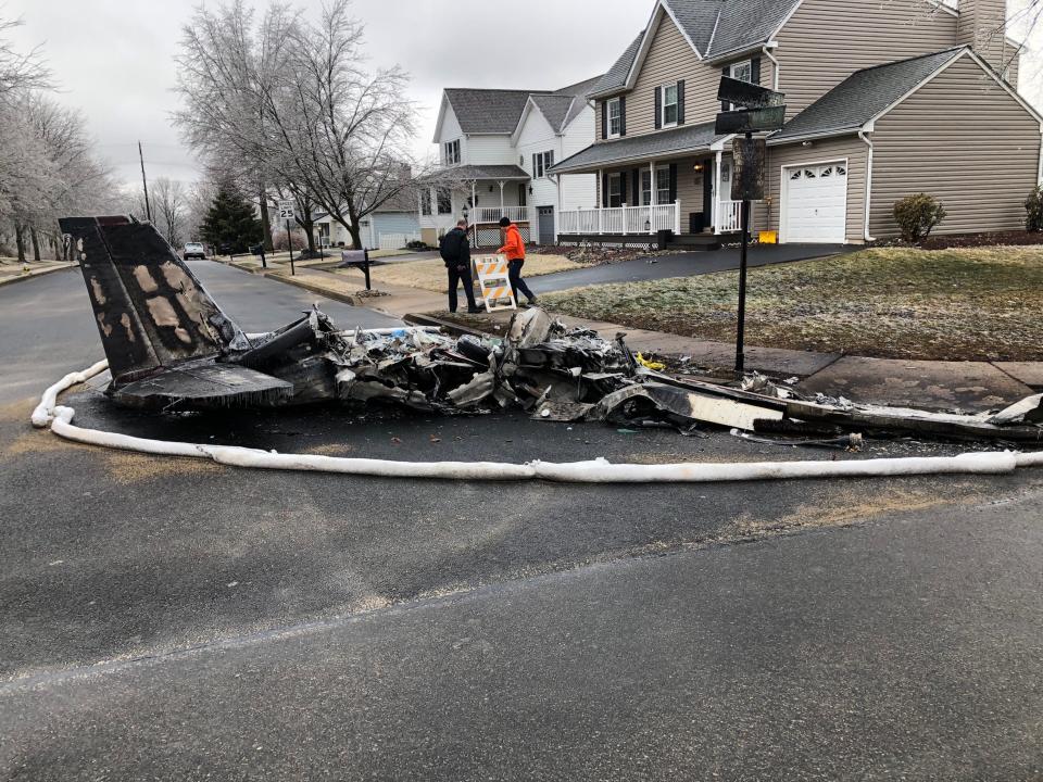 Officers stand near the remains of a single-engine plane that crashed in a Hilltown neighborhood on Thursday, Feb. 24, 2022. Two people in the plane were killed.