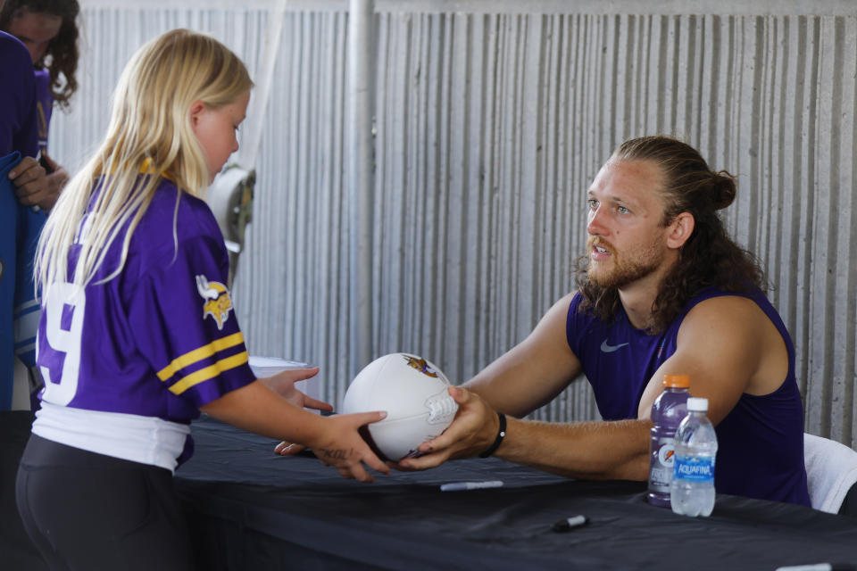 Minnesota Vikings tight end T.J. Hockenson, right, signs an autograph for a fan after practice at NFL football training camp Saturday, July 29, 2023, in Eagan, Minn. (AP Photo/Bruce Kluckhohn)