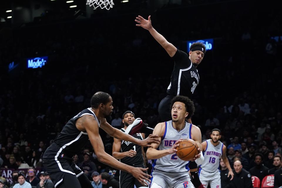 Detroit Pistons' Cade Cunningham (2) protects the ball from Brooklyn Nets' Seth Curry (30) and Kevin Durant during the first half of an NBA basketball game Tuesday, March 29, 2022 in New York. (AP Photo/Frank Franklin II)