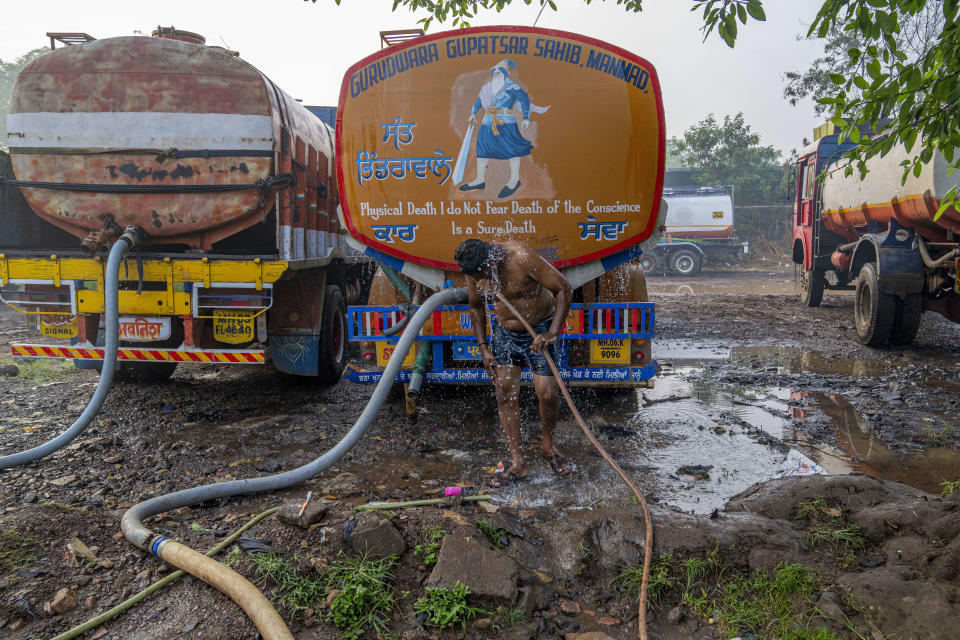 Before being deployed to distant villages to distribute water, a driver of a water tanker cools off with a bath in Sapgaon, northeast of Mumbai, India, Saturday, May 6, 2023. India has been hit with extreme heat this spring and summer, increasing the country's desperation for water. (AP Photo/Dar Yasin)