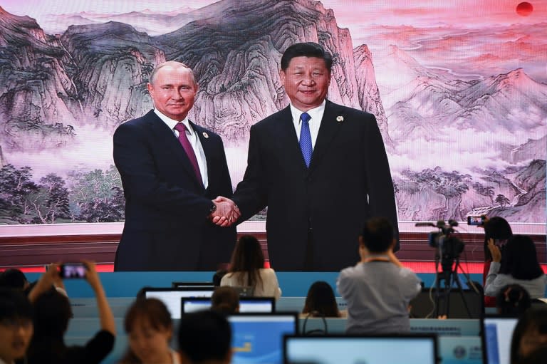 A large video screen shows Chinese President Xi Jinping shaking hands with Russia's President Vladimir Putin before the summit