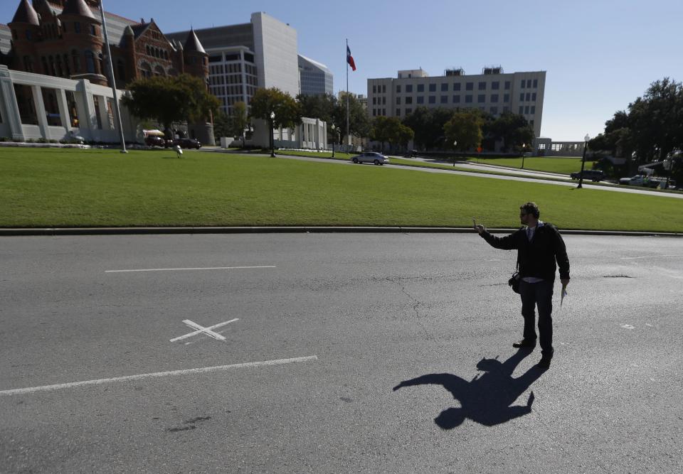 A visitor photographs the x marking the sport where John Fitzgerald Kennedy was shot on Dealey Plaza in downtown Dallas, Tuesday, Nov. 12, 2013. Church bells tolling throughout Dallas and a moment of silence at 12:30 p.m. on Nov. 22 will mark the moment 50 years ago when President John F. Kennedy was assassinated. A year of commemorative events organized by organizations throughout the city culminates this month with a solemn ceremony the city of Dallas has planned in Dealey Plaza, where Kennedy’s motorcade was passing as shots rang out. (AP Photo/LM Otero)