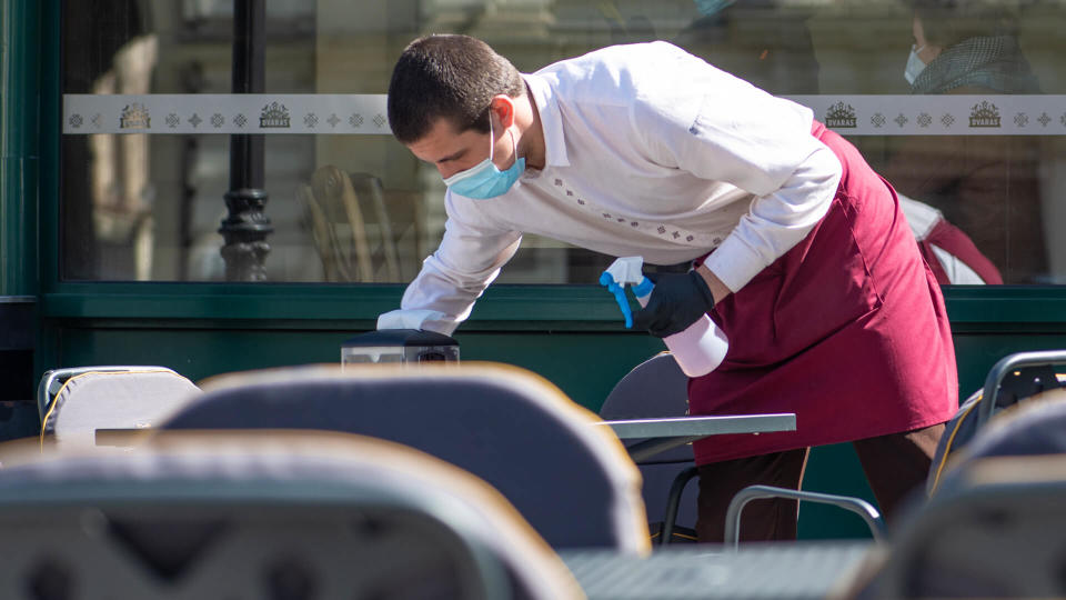 Vilnius, Lithuania - April 30 2020: Waiter with a mask disinfects the table of an outdoor bar, café or restaurant, reopen after quarantine restrictions.